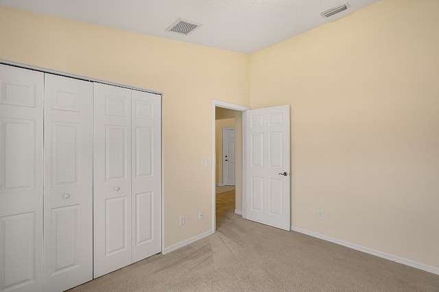 unfurnished bedroom with light carpet and a closet