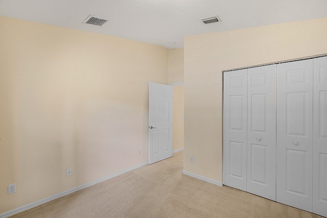 unfurnished bedroom with a closet and light colored carpet