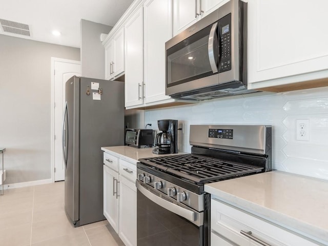 kitchen with appliances with stainless steel finishes, light tile patterned floors, decorative backsplash, and white cabinets