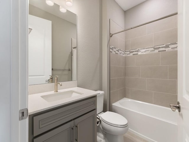 full bathroom featuring vanity, tiled shower / bath, and toilet