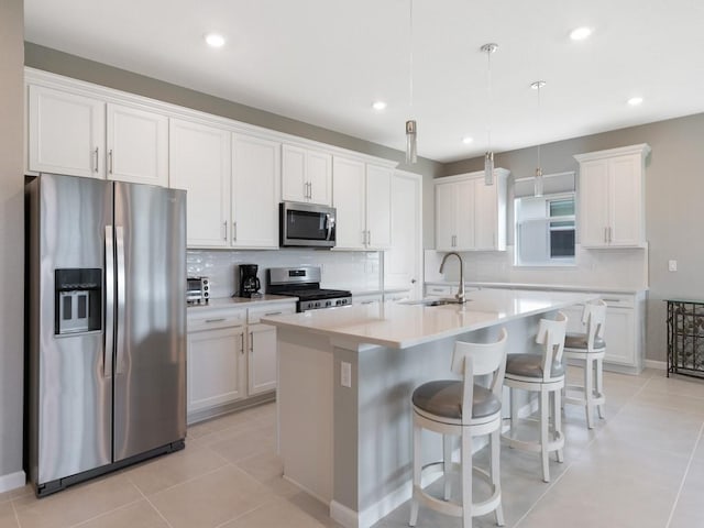 kitchen featuring white cabinetry, stainless steel appliances, and a center island with sink