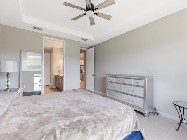 tiled bedroom featuring ceiling fan, connected bathroom, and a tray ceiling