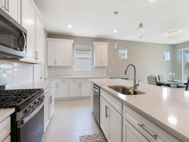 kitchen with appliances with stainless steel finishes, sink, white cabinets, and decorative light fixtures