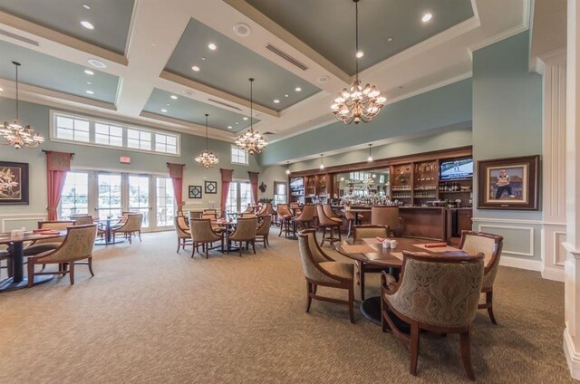 1544 Par Ct, Vero Beach, FL 32966 - dining space featuring carpet flooring, a high ceiling, a chandelier, a decorative wall, and crown molding
