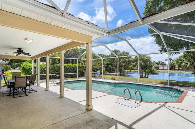 outdoor pool featuring a patio area, a ceiling fan, glass enclosure, and a water view