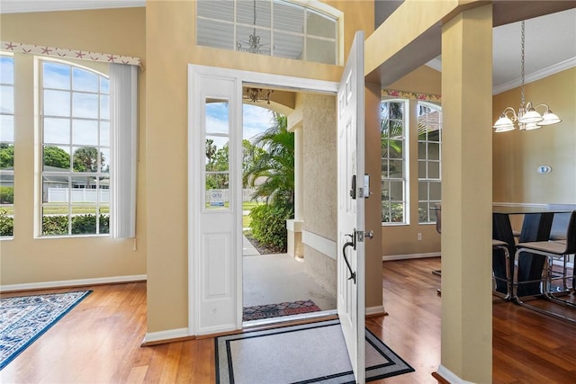 doorway to outside featuring a chandelier, wood finished floors, baseboards, and plenty of natural light