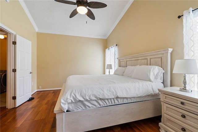 bedroom featuring dark wood-type flooring, washer / dryer, vaulted ceiling, and crown molding