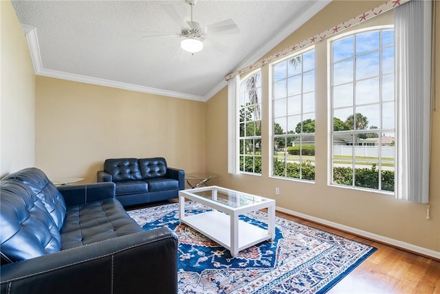living area with wood finished floors, ornamental molding, vaulted ceiling, and plenty of natural light