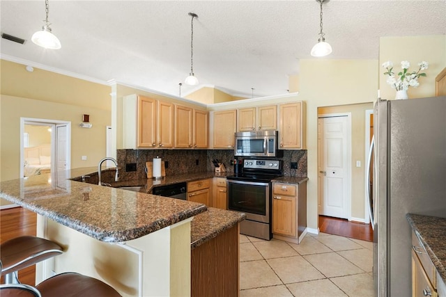 kitchen featuring light tile patterned floors, a kitchen bar, a peninsula, stainless steel appliances, and decorative backsplash