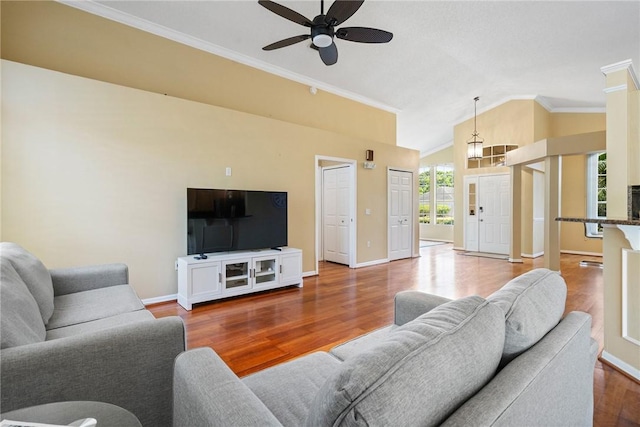 living area with lofted ceiling, baseboards, crown molding, ceiling fan, and wood finished floors