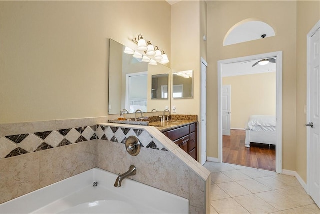 ensuite bathroom featuring a garden tub, ensuite bathroom, vanity, tile patterned floors, and baseboards