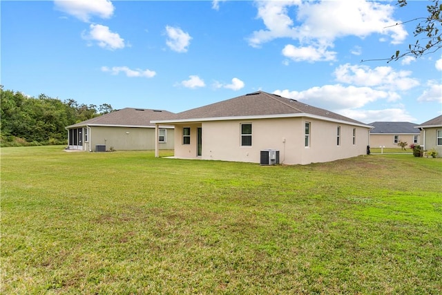 back of house with central AC unit and a lawn