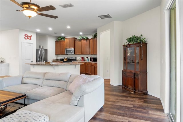 living room with ceiling fan and dark hardwood / wood-style flooring