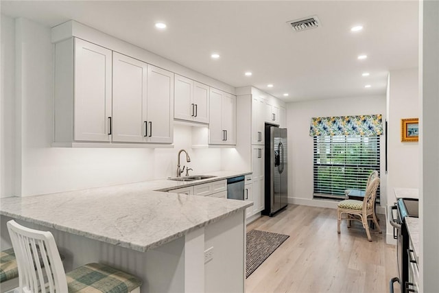 kitchen with kitchen peninsula, white cabinetry, sink, and appliances with stainless steel finishes