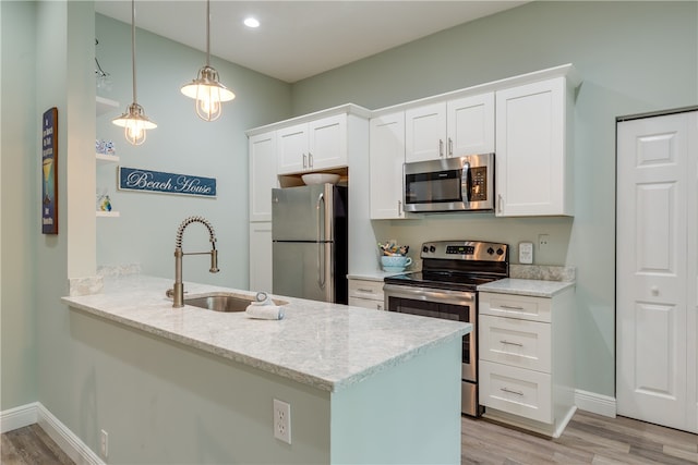 kitchen with kitchen peninsula, appliances with stainless steel finishes, decorative light fixtures, white cabinets, and light wood-type flooring