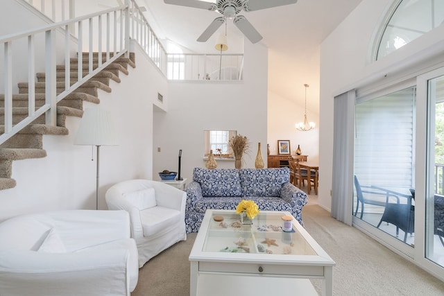 carpeted living room with high vaulted ceiling and ceiling fan with notable chandelier