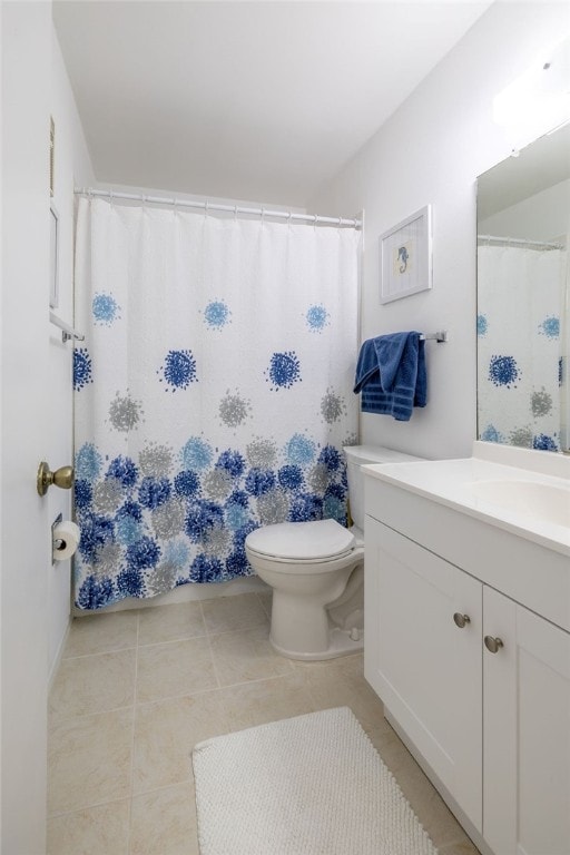 bathroom with toilet, vanity, and tile patterned flooring