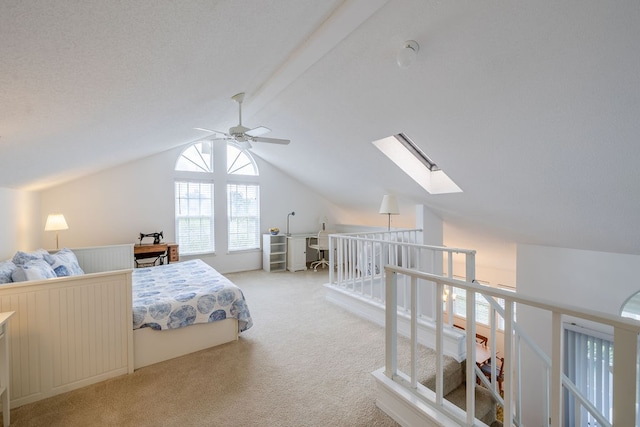 carpeted bedroom featuring lofted ceiling with skylight and ceiling fan