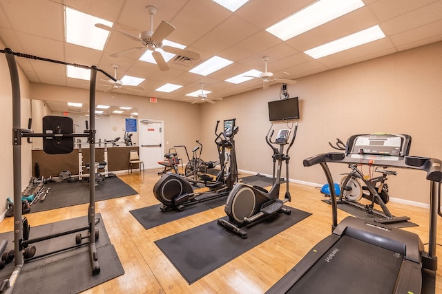 exercise room with light hardwood / wood-style floors, a paneled ceiling, and ceiling fan