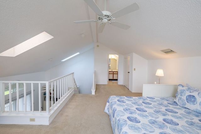 carpeted bedroom featuring vaulted ceiling with skylight and ceiling fan