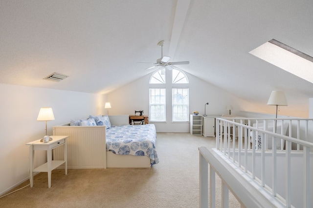 carpeted bedroom with a textured ceiling, ceiling fan, and lofted ceiling with skylight