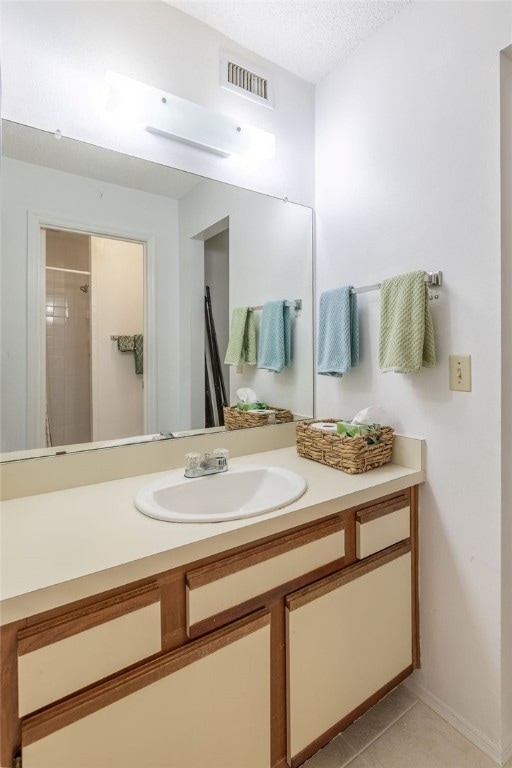 bathroom with vanity, walk in shower, tile patterned floors, and a textured ceiling