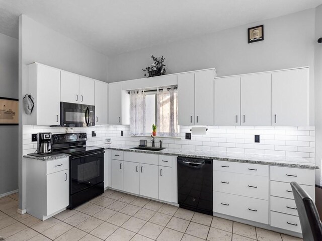 kitchen featuring sink, white cabinets, backsplash, light stone counters, and black appliances