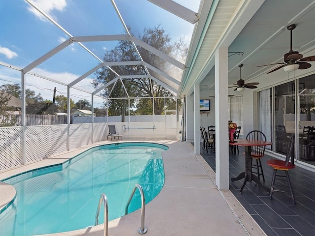 view of pool with a patio area, ceiling fan, and glass enclosure