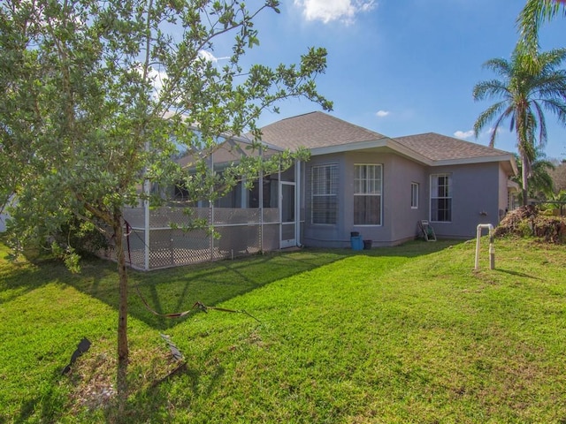 rear view of property with a lawn and glass enclosure