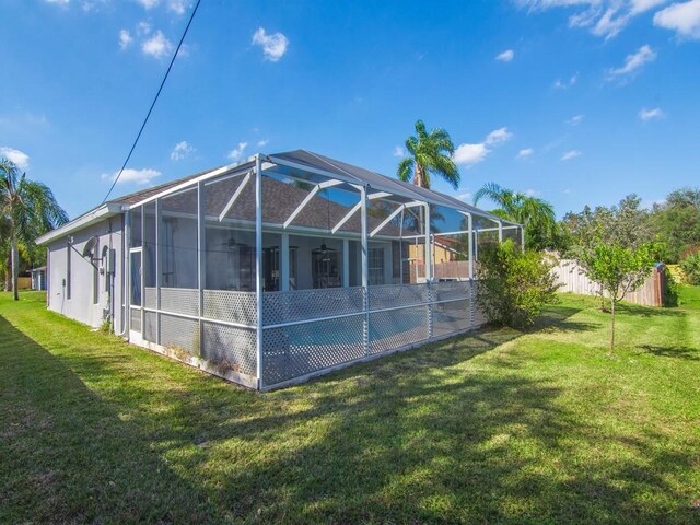 rear view of property with a yard and glass enclosure