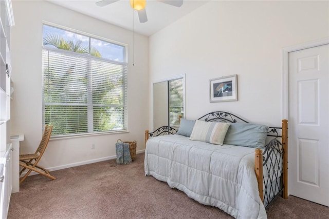 carpeted bedroom featuring ceiling fan and a high ceiling