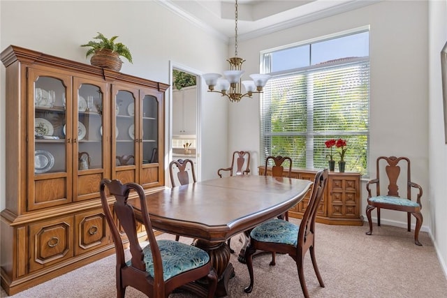 dining room with light carpet, a notable chandelier, and ornamental molding