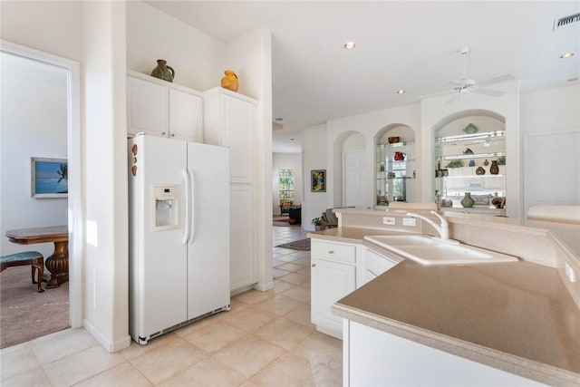 kitchen featuring white cabinetry, white refrigerator with ice dispenser, sink, and light tile patterned flooring