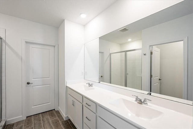 bathroom featuring a stall shower, double vanity, wood tiled floors, and recessed lighting
