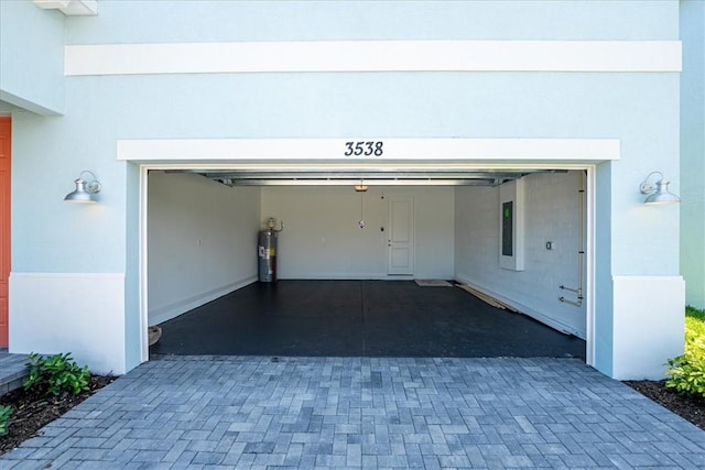 garage featuring electric water heater and decorative driveway