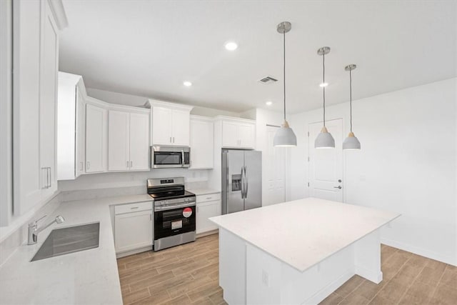 kitchen featuring appliances with stainless steel finishes, a sink, light wood-style flooring, a center island, and recessed lighting