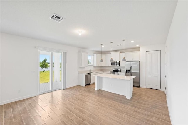 kitchen with appliances with stainless steel finishes, a sink, light countertops, white cabinets, and light wood-type flooring