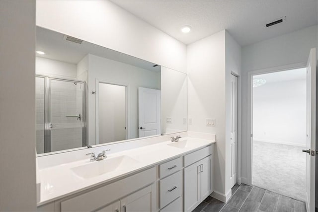 bathroom with double vanity, a stall shower, baseboards, and recessed lighting