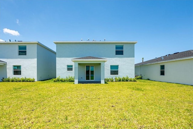 back of property featuring a lawn and stucco siding