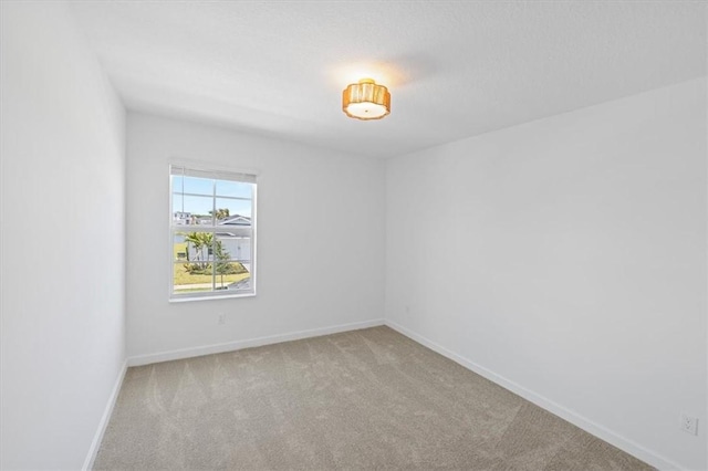 unfurnished room featuring light colored carpet and baseboards