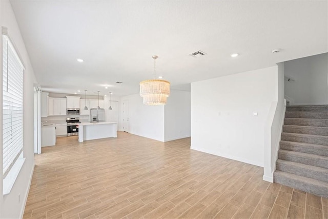 unfurnished living room with plenty of natural light, light wood-type flooring, stairway, and recessed lighting