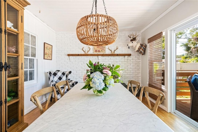 dining area featuring light hardwood / wood-style flooring, ornamental molding, and brick wall