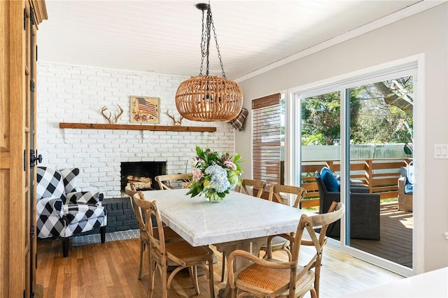 dining room with crown molding, a fireplace, and light wood-type flooring