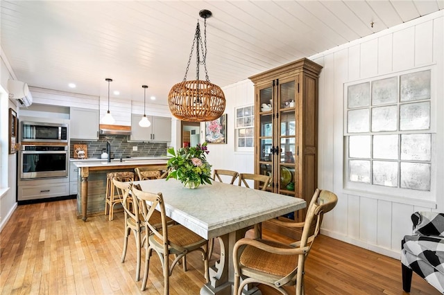 dining room with sink, a wall mounted air conditioner, wooden ceiling, and light wood-type flooring