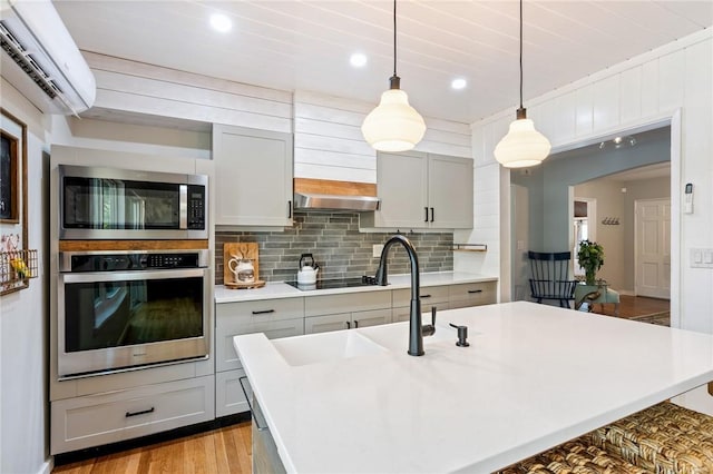 kitchen featuring gray cabinetry, tasteful backsplash, an AC wall unit, and appliances with stainless steel finishes