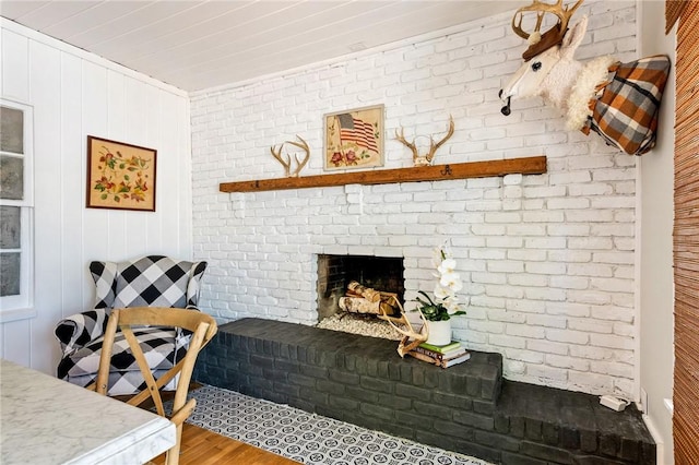 living room featuring hardwood / wood-style flooring, brick wall, and a fireplace