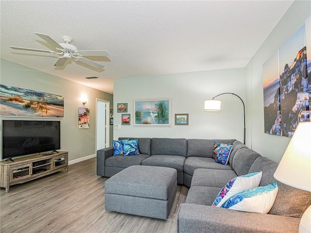 living room with ceiling fan, wood-type flooring, and a textured ceiling