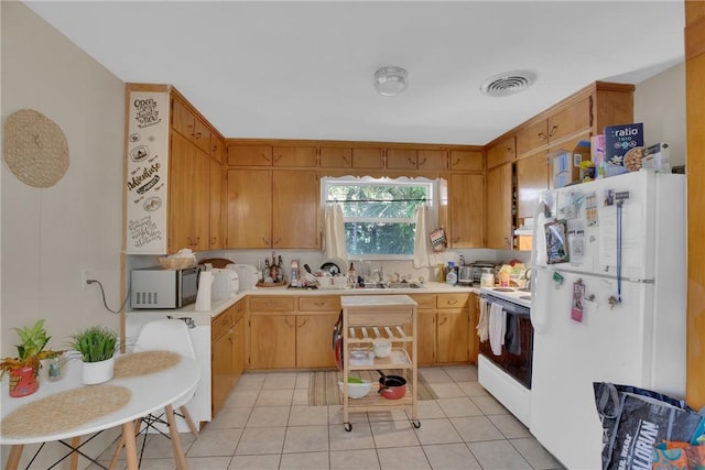 kitchen featuring visible vents, light countertops, light tile patterned floors, white appliances, and a sink