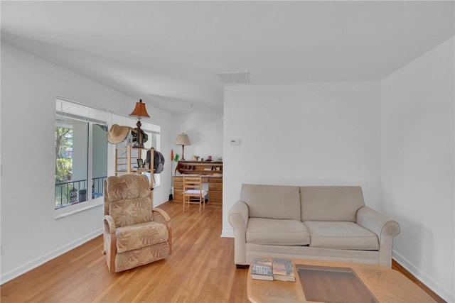 living room featuring baseboards, visible vents, and light wood finished floors