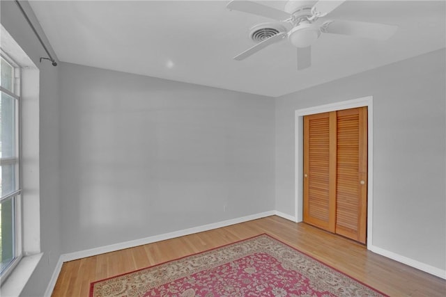 unfurnished bedroom with wood finished floors, visible vents, a closet, and baseboards